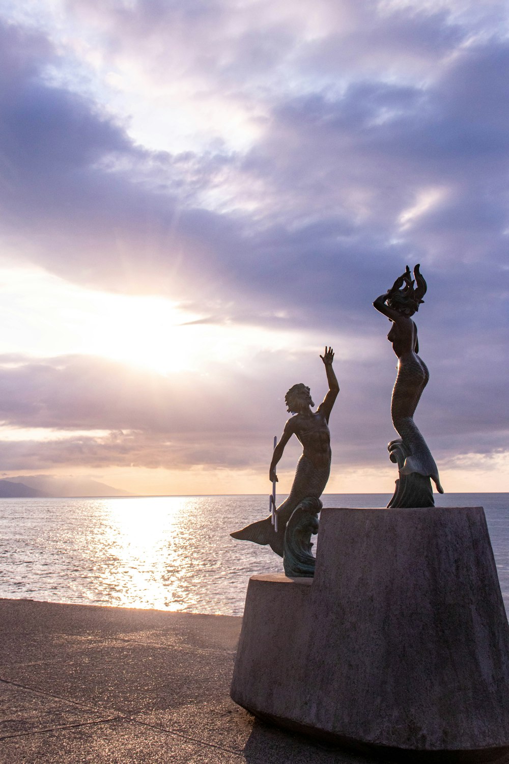 Un par de estatuas sentadas encima de una losa de cemento