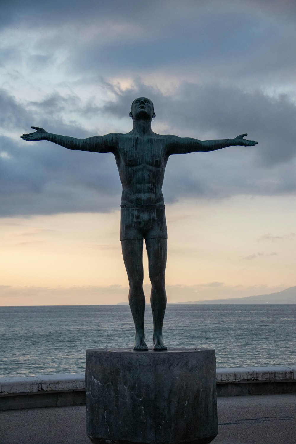 uma estátua de um homem em pé na frente de um corpo de água