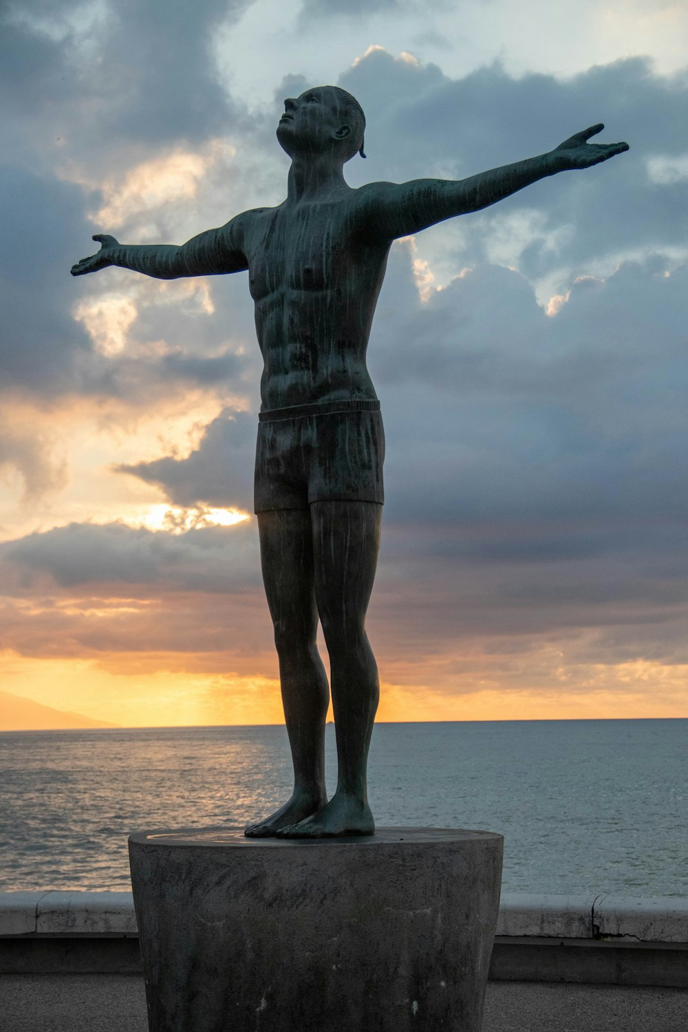 Una estatua de un hombre parado frente a un cuerpo de agua
