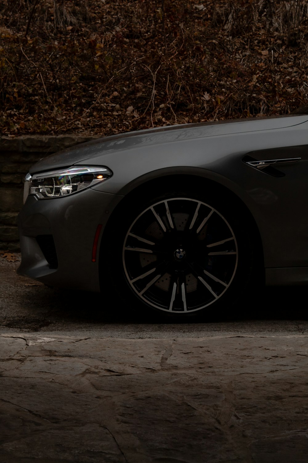 a grey car parked in front of a stone wall