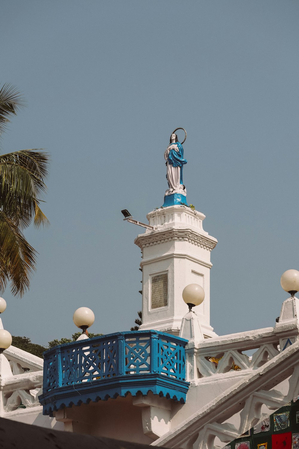 una torre del reloj azul y blanco con una estatua en la parte superior