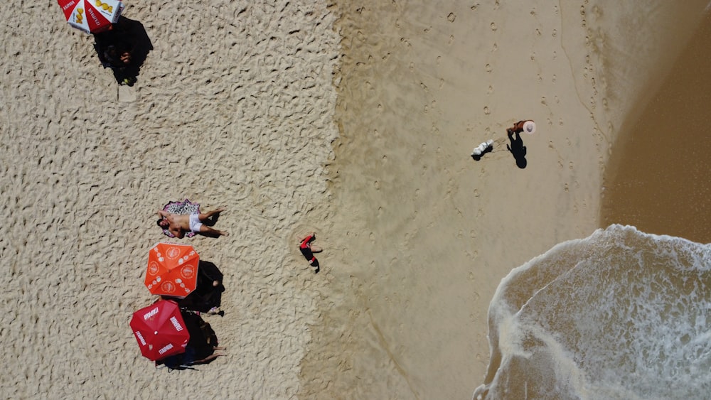 an aerial view of people on a beach with umbrellas