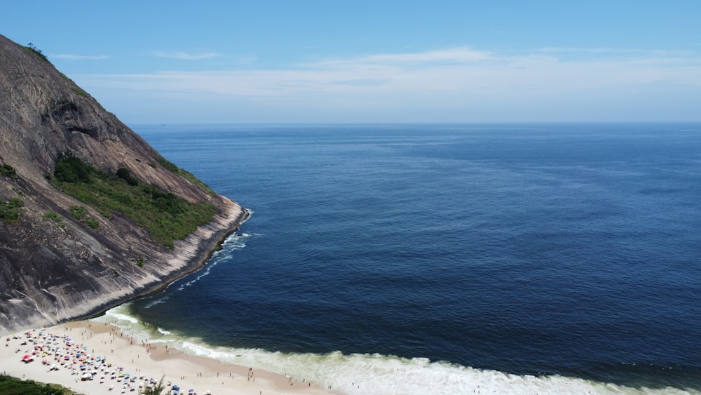 a group of people standing on top of a beach next to the ocean