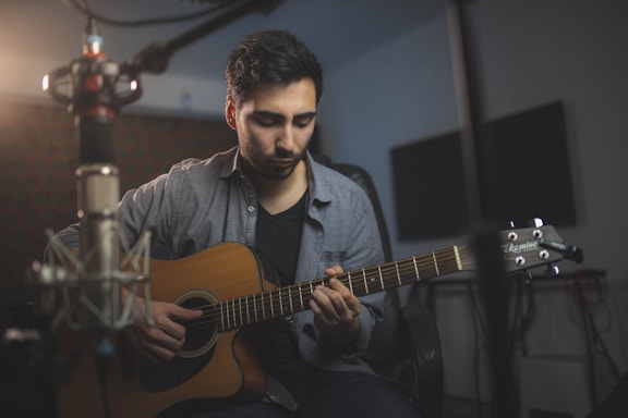 a man playing a guitar in a recording studio