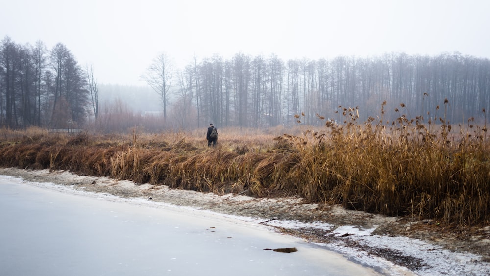 a man standing in a field next to a body of water