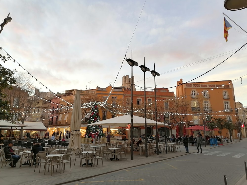 a group of people sitting at tables in a city square