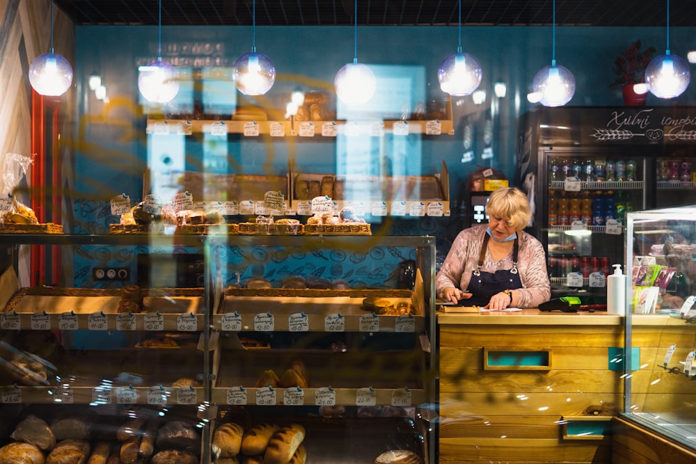a woman standing behind a counter in a bakery
