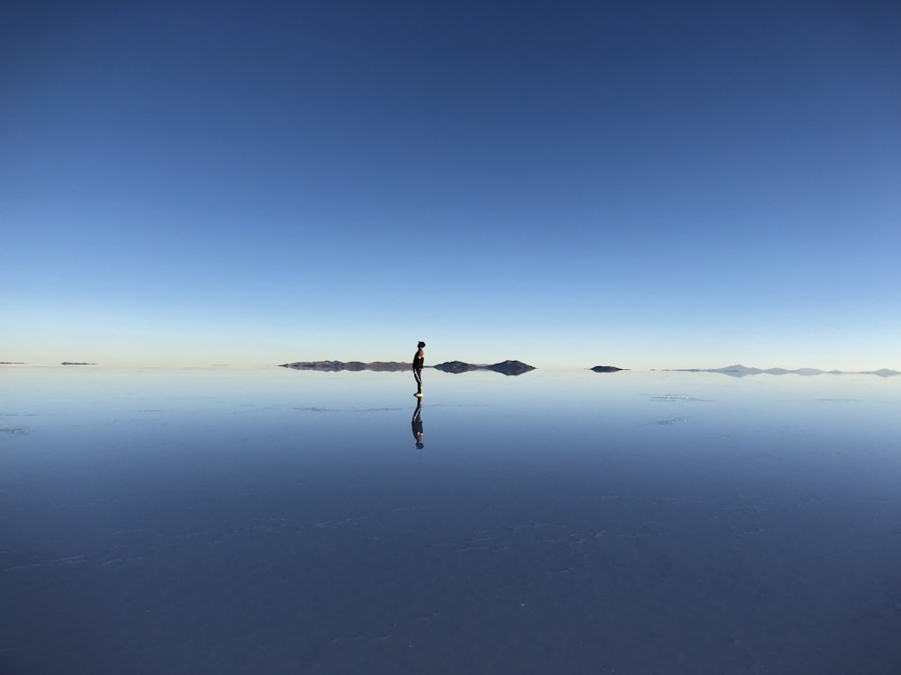 a lone person standing in the middle of a large body of water