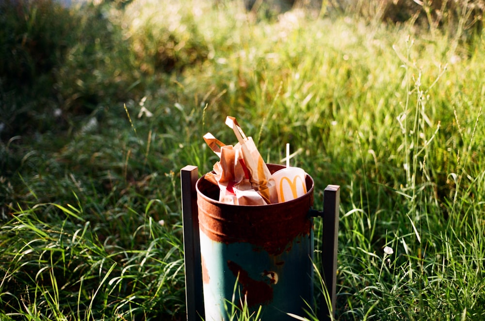 a cup with an umbrella sticking out of it sitting in the grass