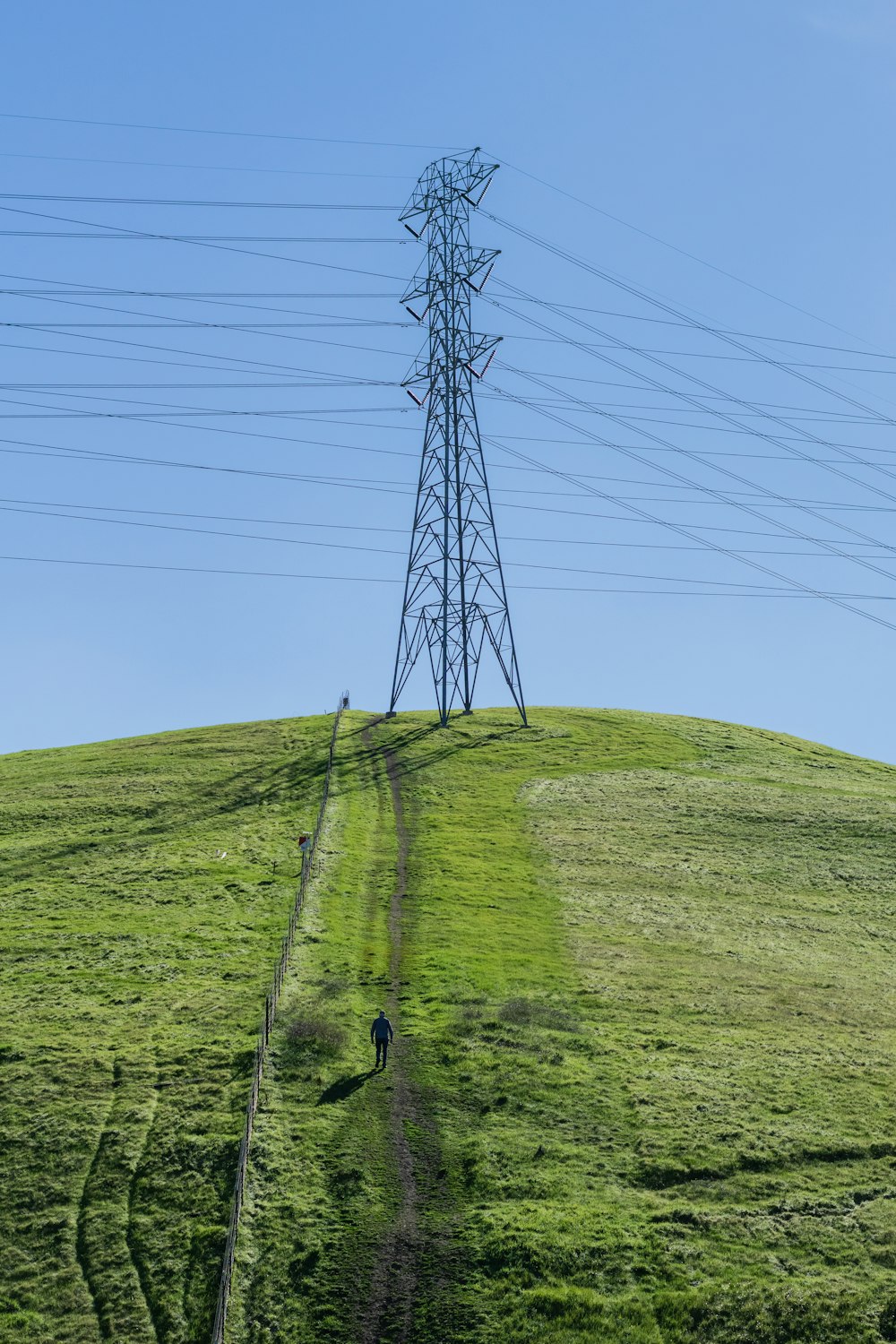 a person walking up a hill with power lines in the background