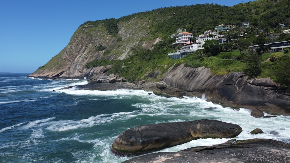 a rocky shore with houses on a hill in the background