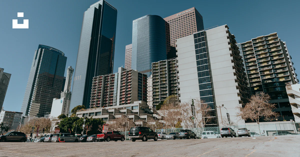 A parking lot in front of some tall buildings photo – Free High rise ...