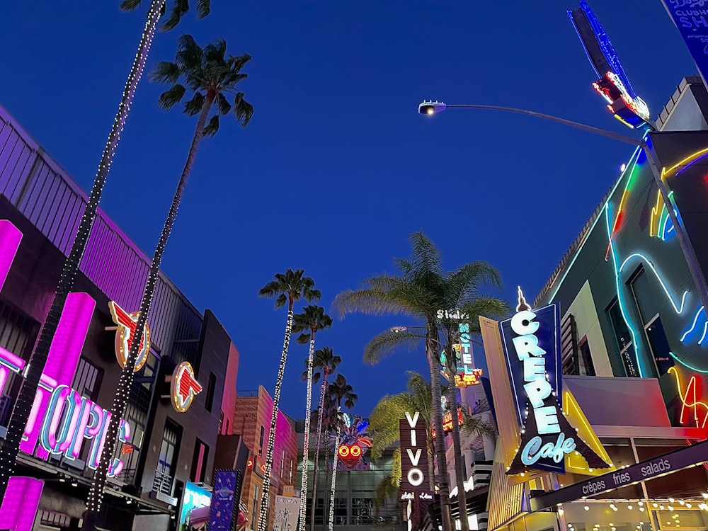 a city street filled with neon signs and palm trees