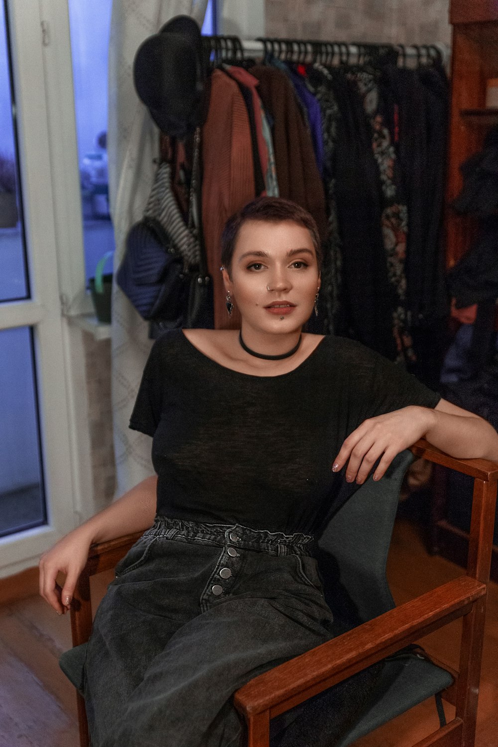 Una mujer sentada en una silla frente a un estante de ropa