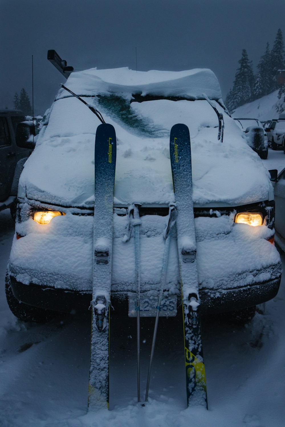 a car covered in snow with skis on top of it