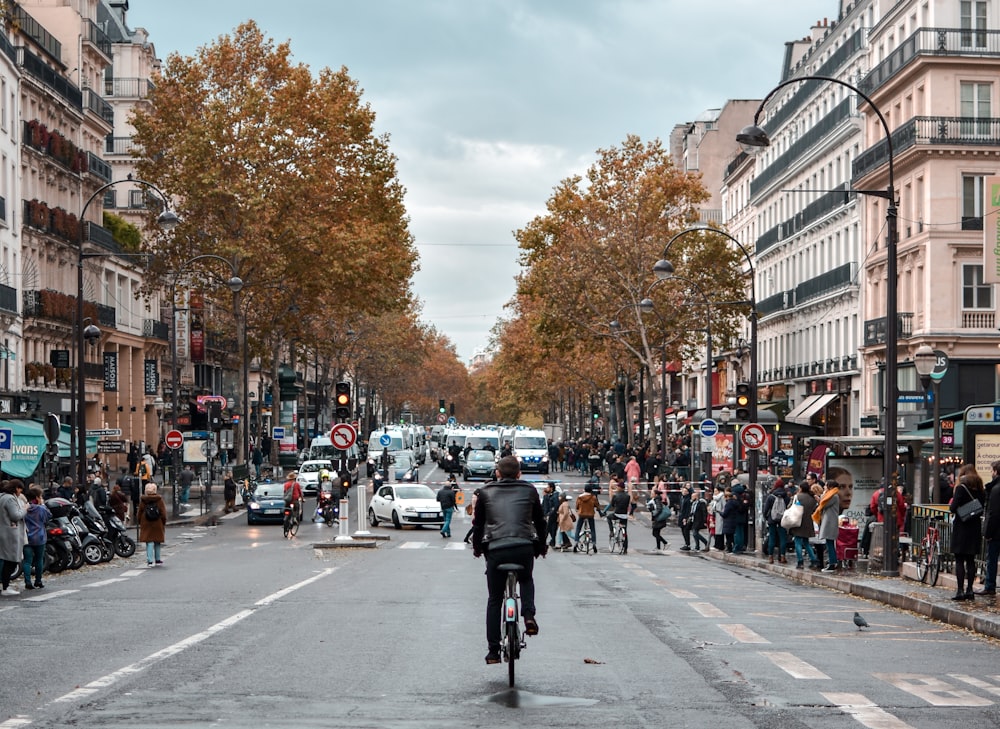 a man riding a bike down a street next to tall buildings