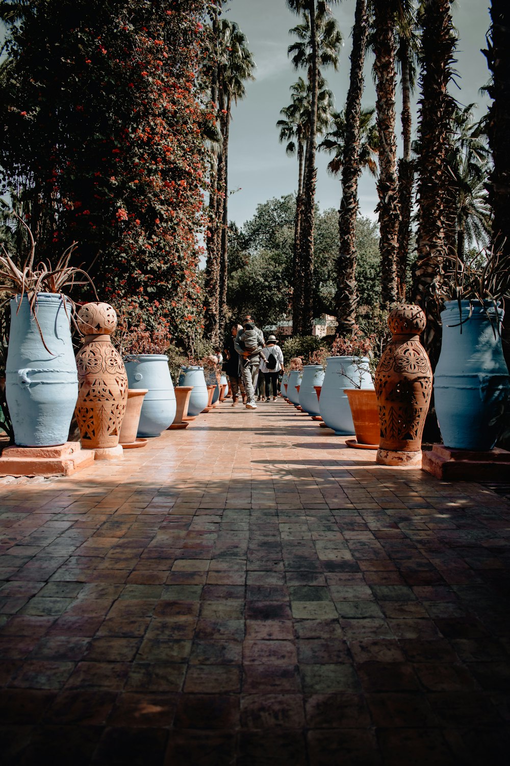 a group of large blue vases sitting on top of a brick walkway