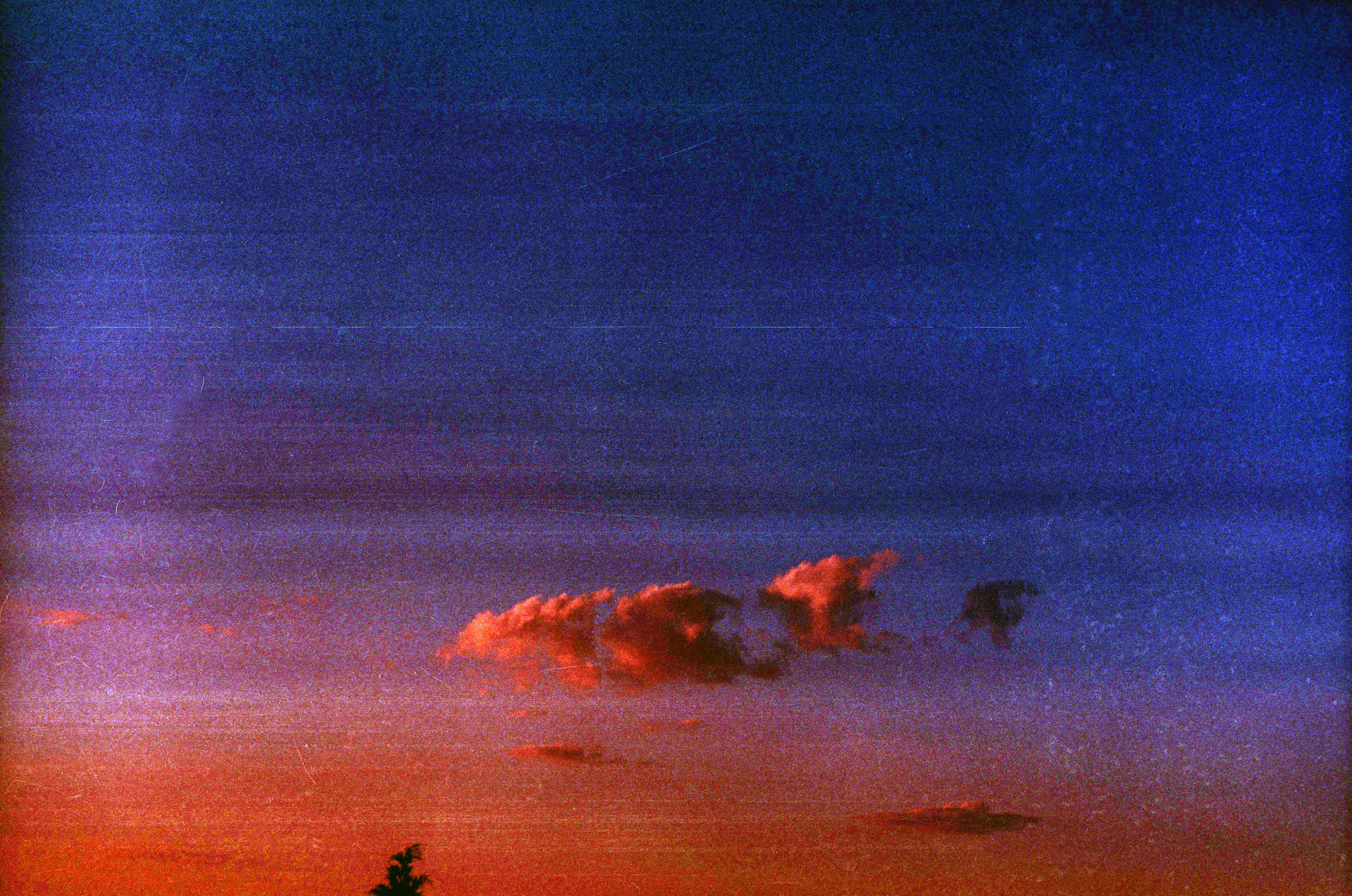 a red and blue sky with clouds and trees