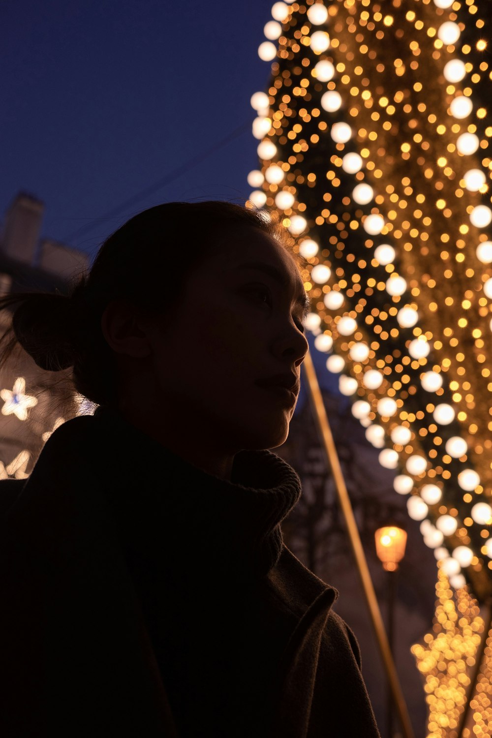 a woman standing in front of a christmas tree