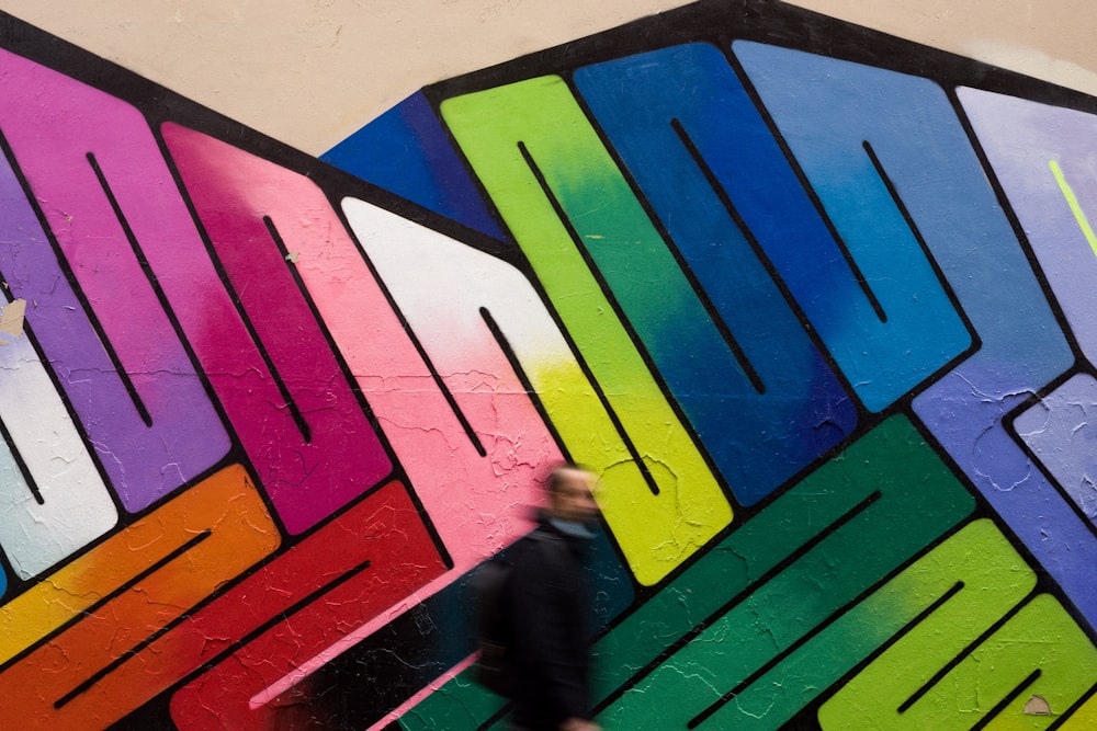 a person walking past a wall with a colorful mural on it