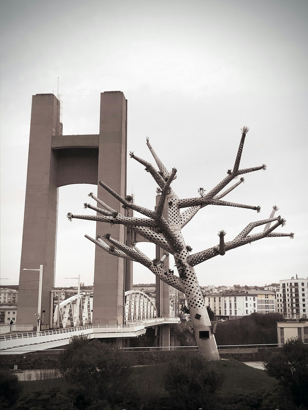 a sculpture of a tree in front of a bridge