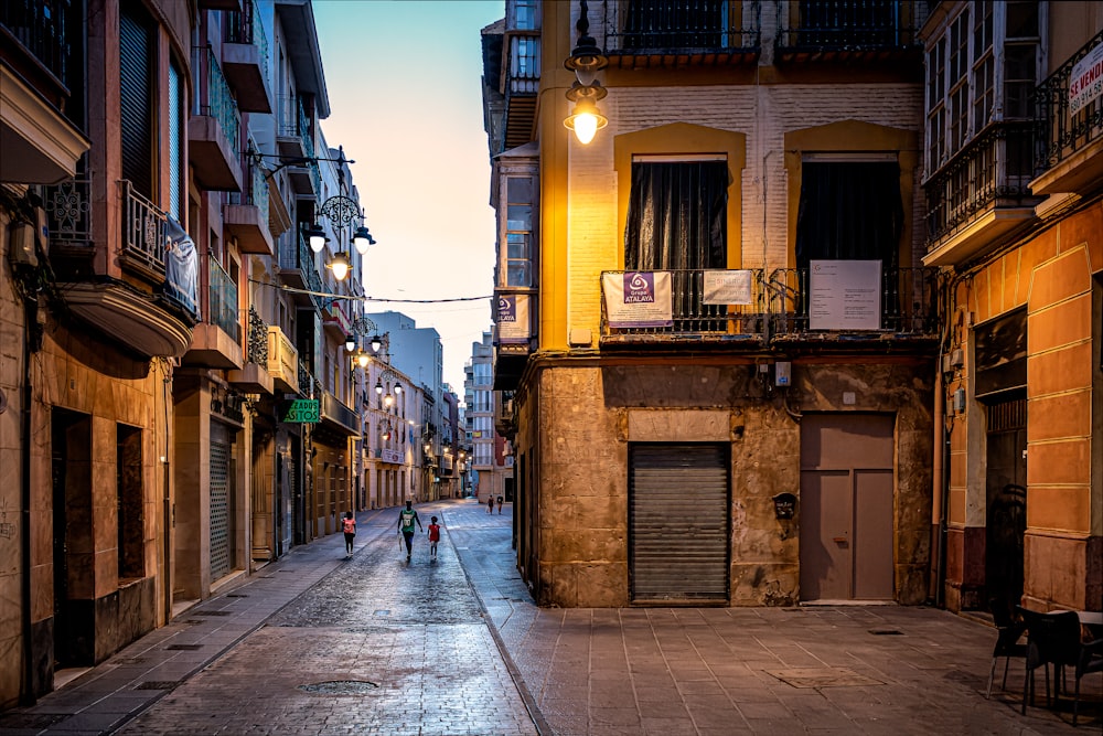 a narrow city street with people walking down it