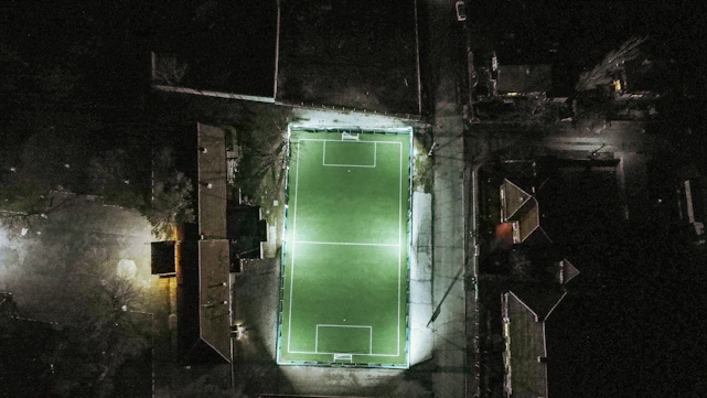 dark-themed football pitch with neon green data overlays and a focused analyst at work