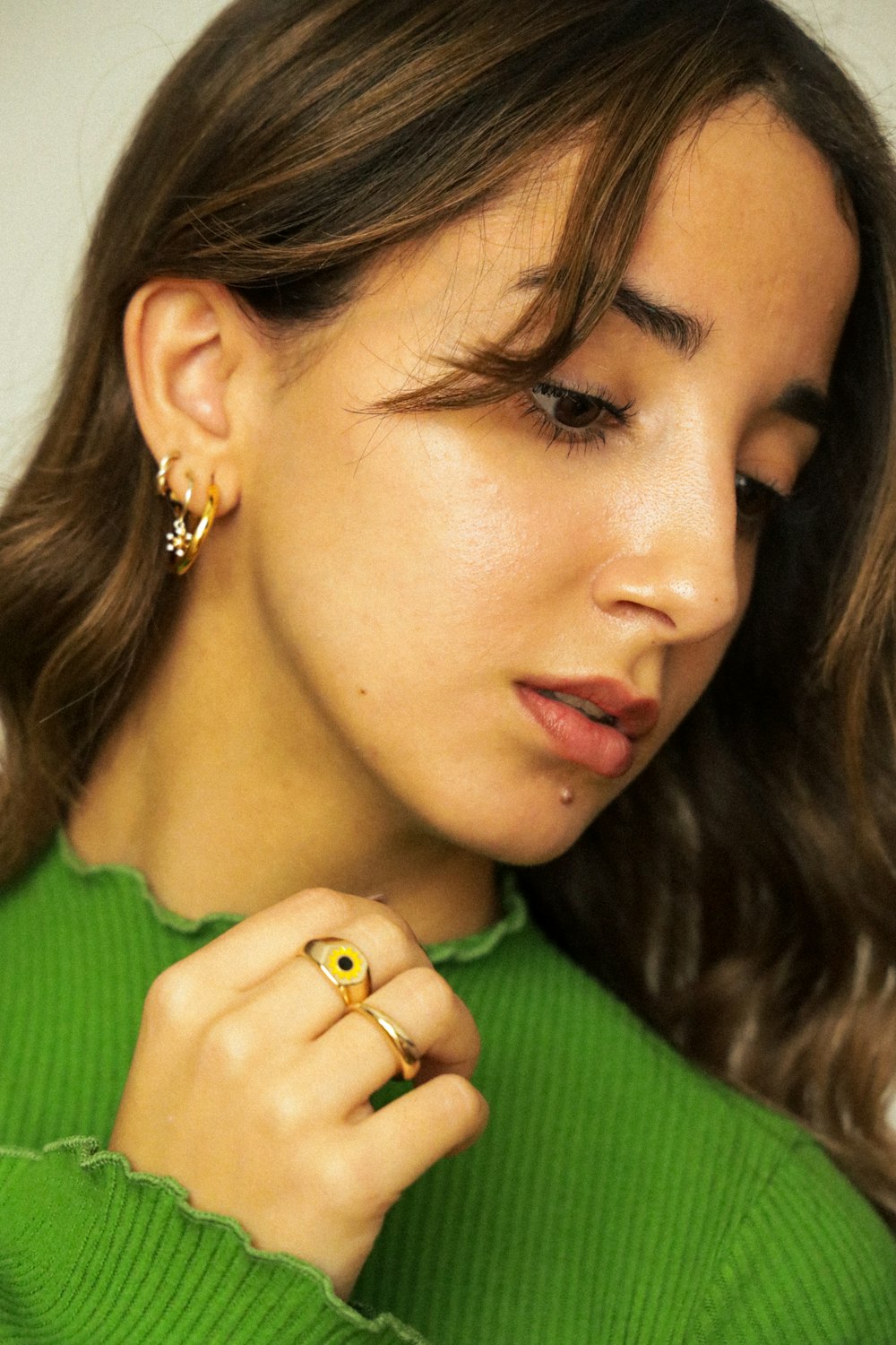 a woman wearing a green sweater and a pair of earrings
