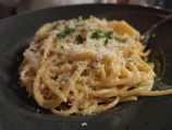 Creamy pasta dish garnished with herbs, served steaming hot.