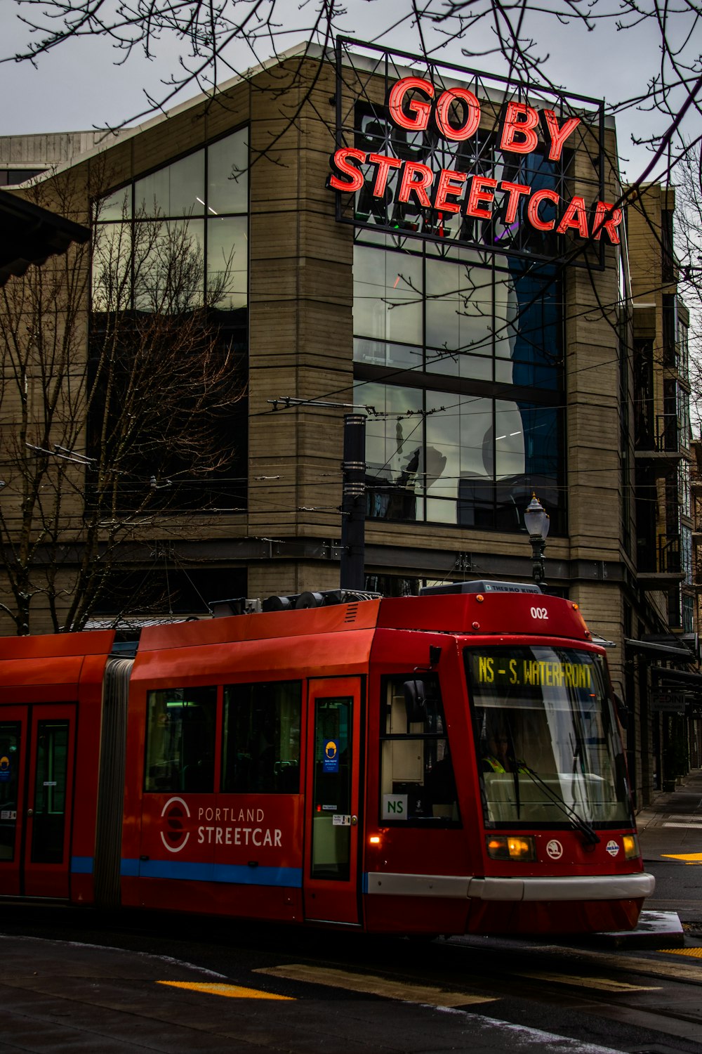 a red train traveling past a tall building