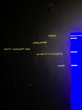 A sleek yellow Upnet logo brightly standing out on a moody dark textured wall.