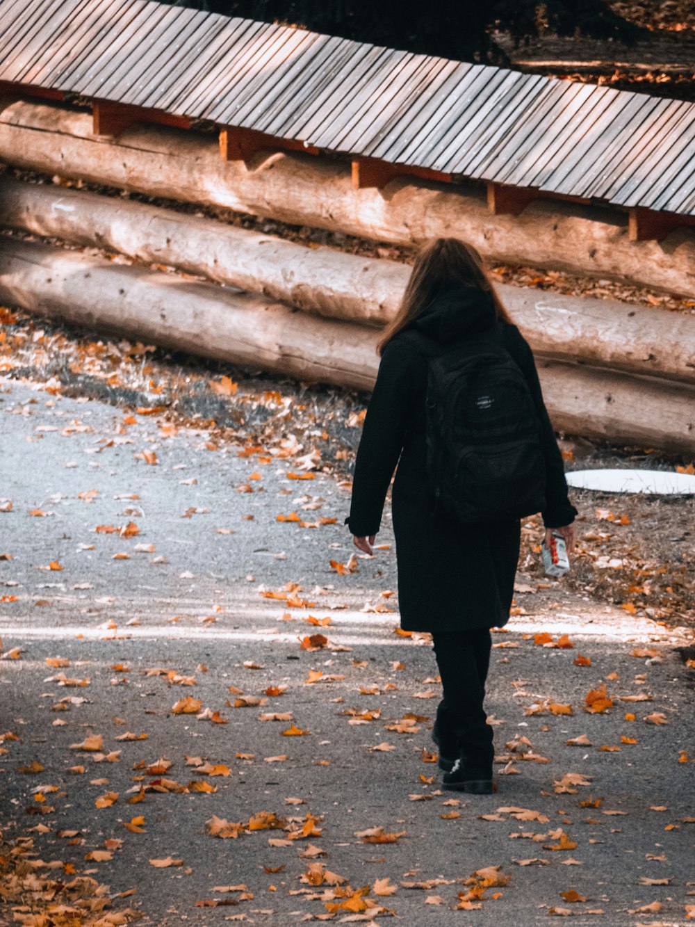 a woman walking down a road in the fall