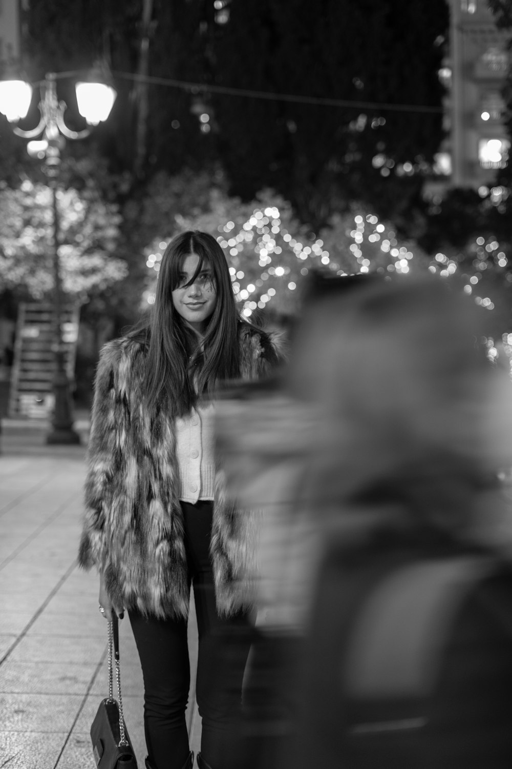 a woman in a fur coat standing on a sidewalk