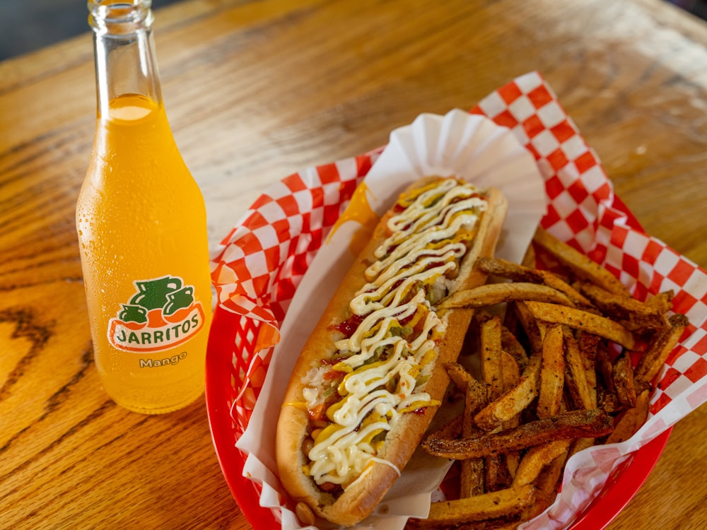 a hot dog in a basket next to a bottle of soda