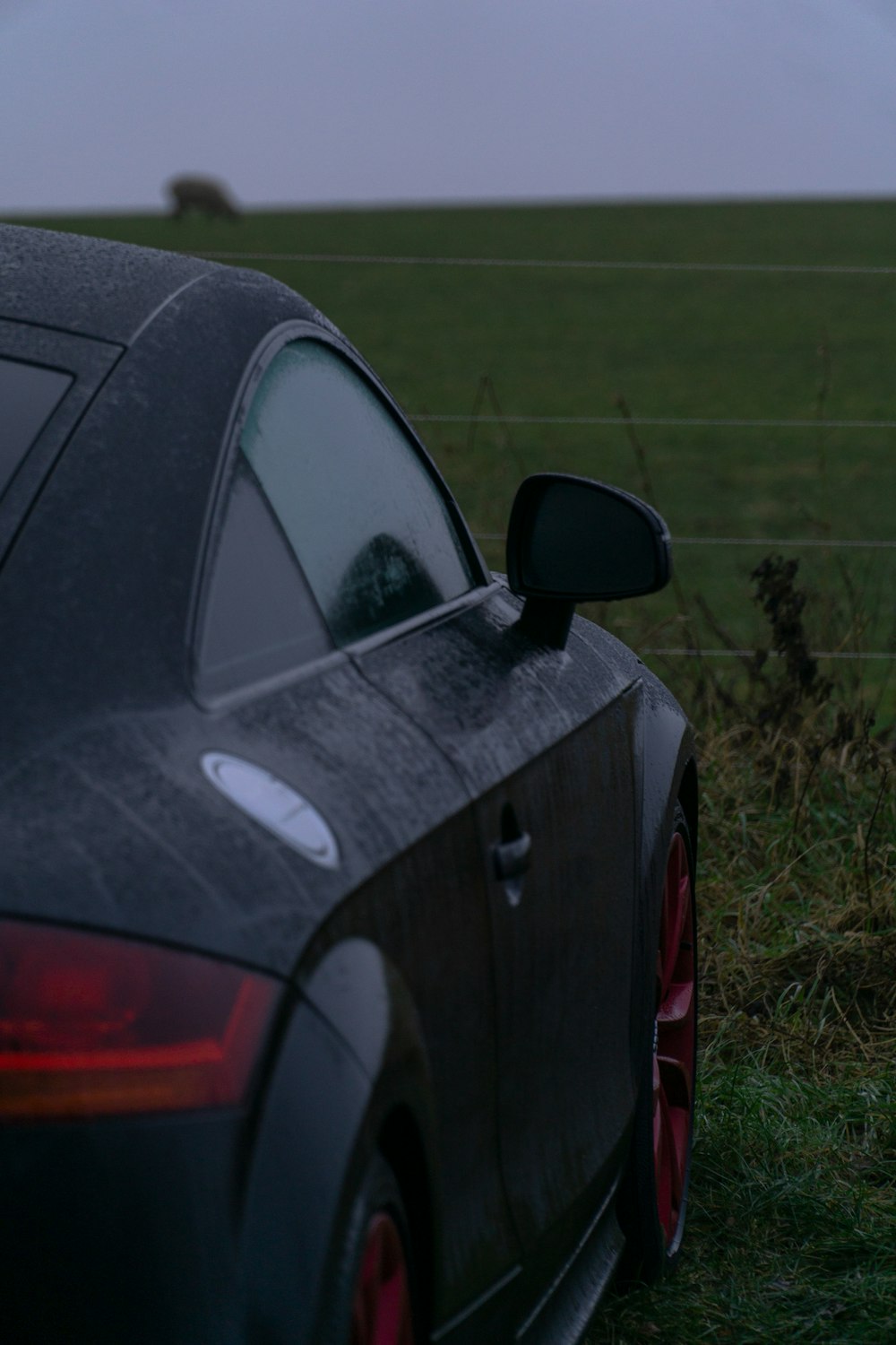 a car parked in a field with a fence in the background