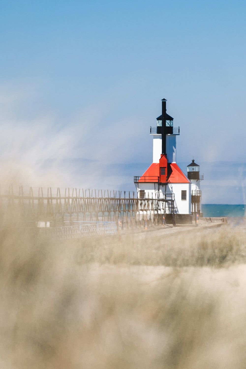 a red and white lighthouse sitting on top of a sandy beach