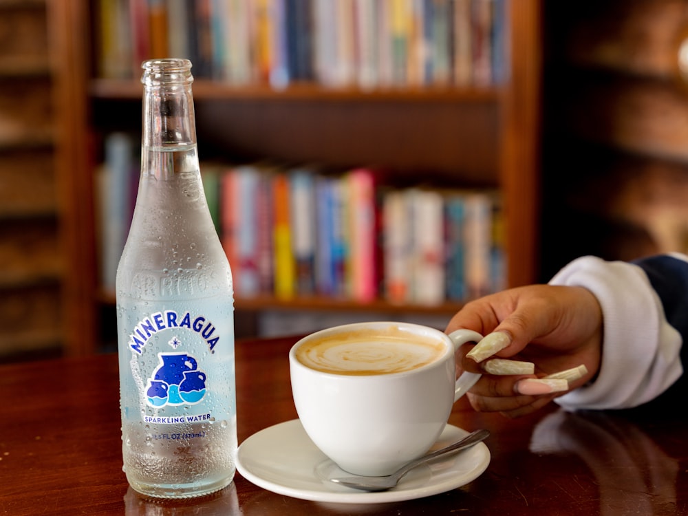 una taza de café y una botella de agua sobre una mesa