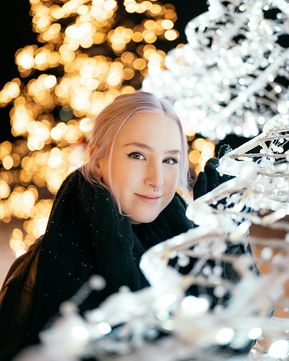 a woman is posing for a picture in front of a christmas tree