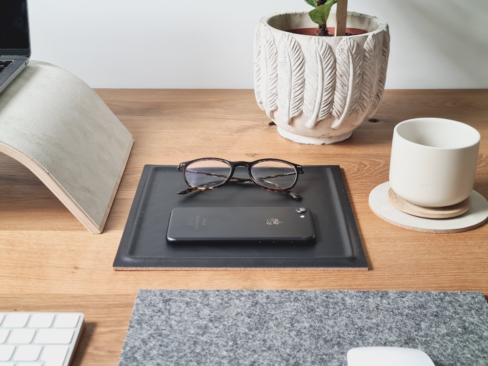 a desk with a laptop, mouse and glasses on it