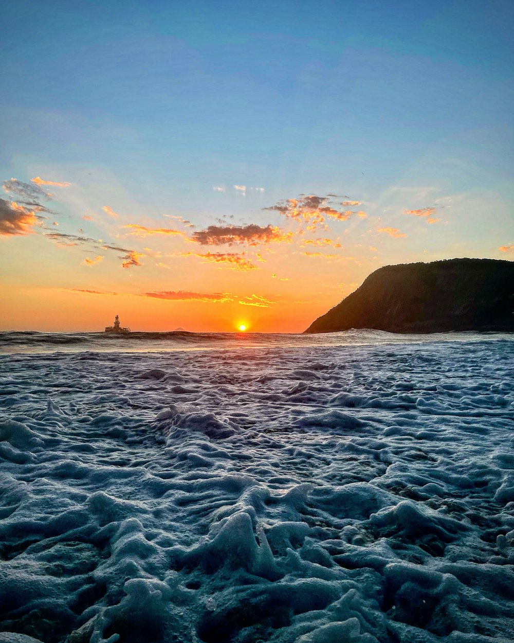 the sun is setting over the ocean with waves