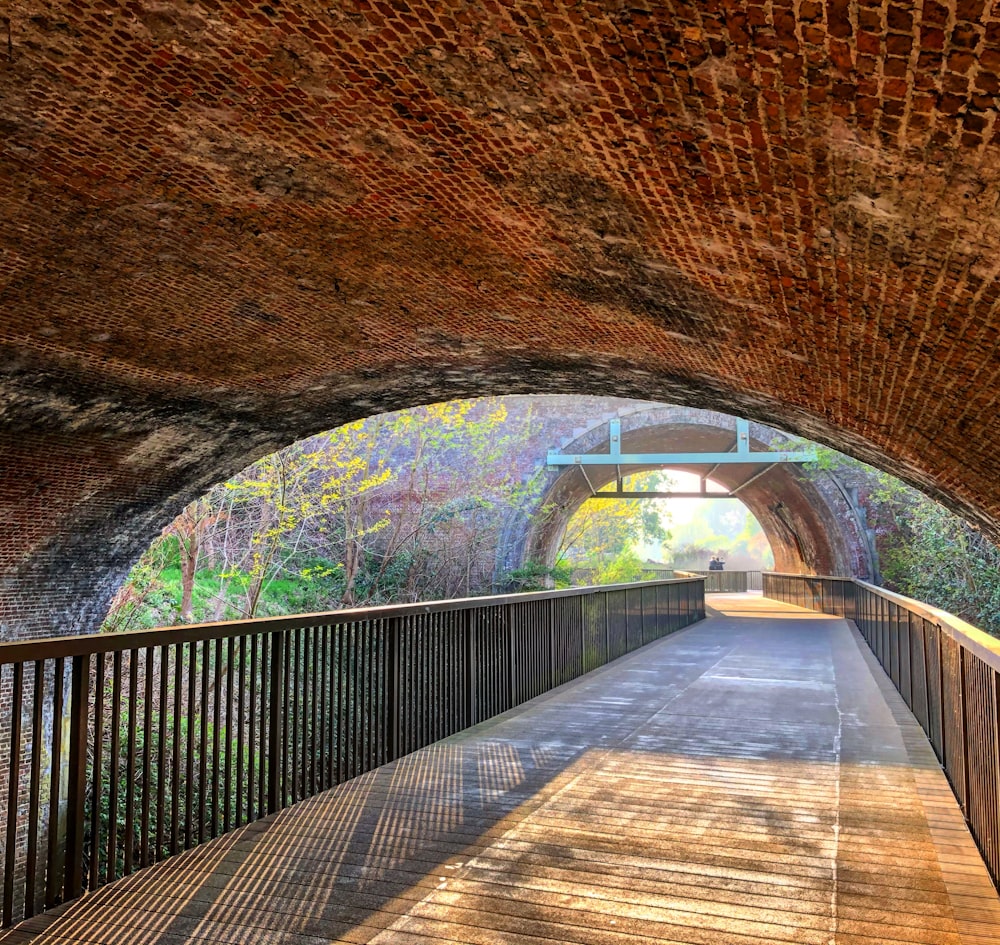 a walkway under a bridge with a light at the end