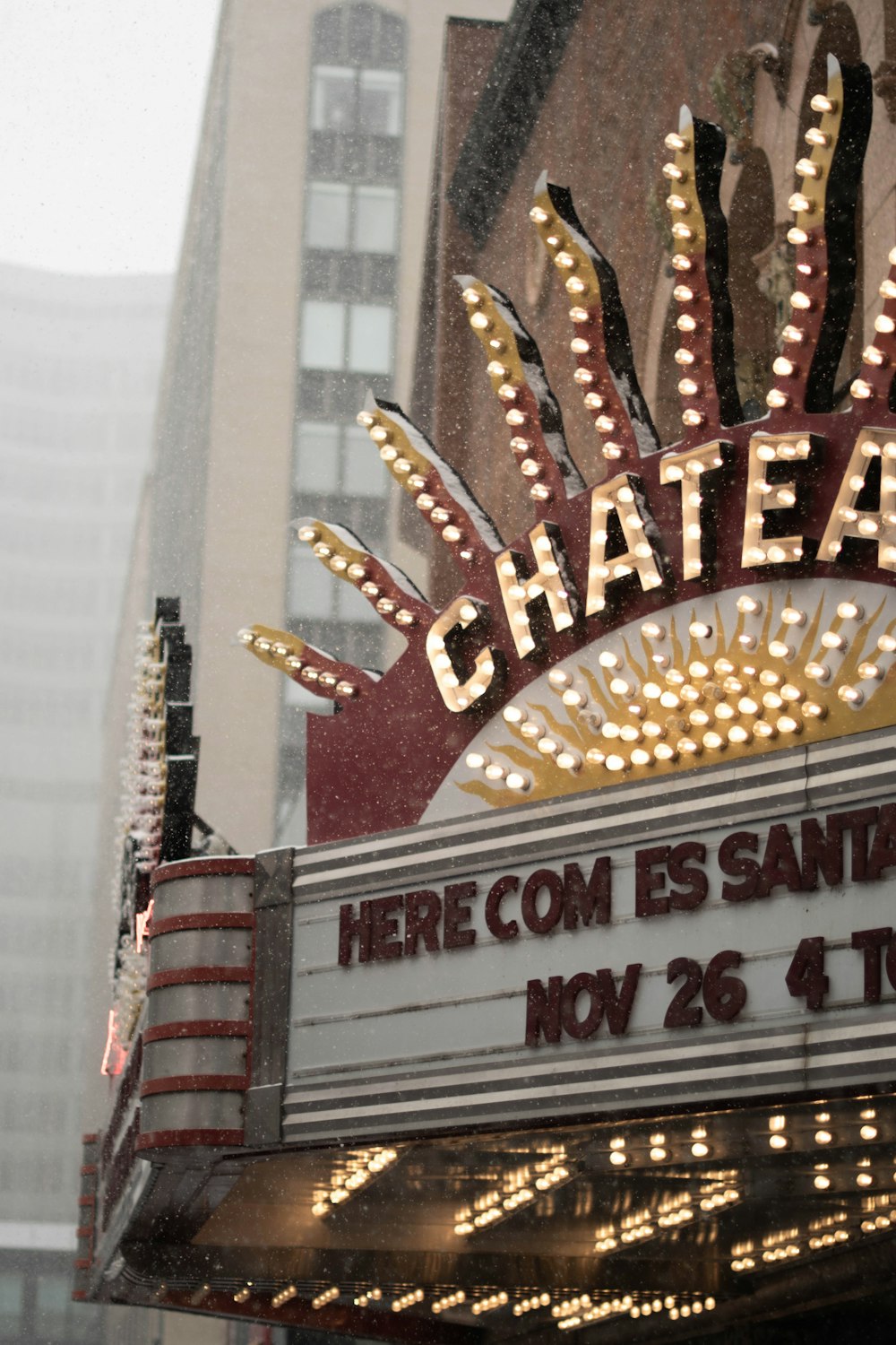 a theater marquee with lights on in the rain