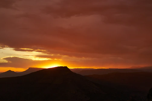 A cinematic video still showing a dramatic sunset over a mountain range.