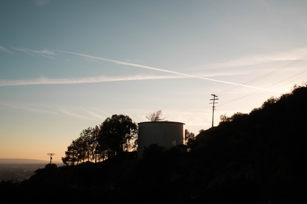 the sun is setting behind a water tower