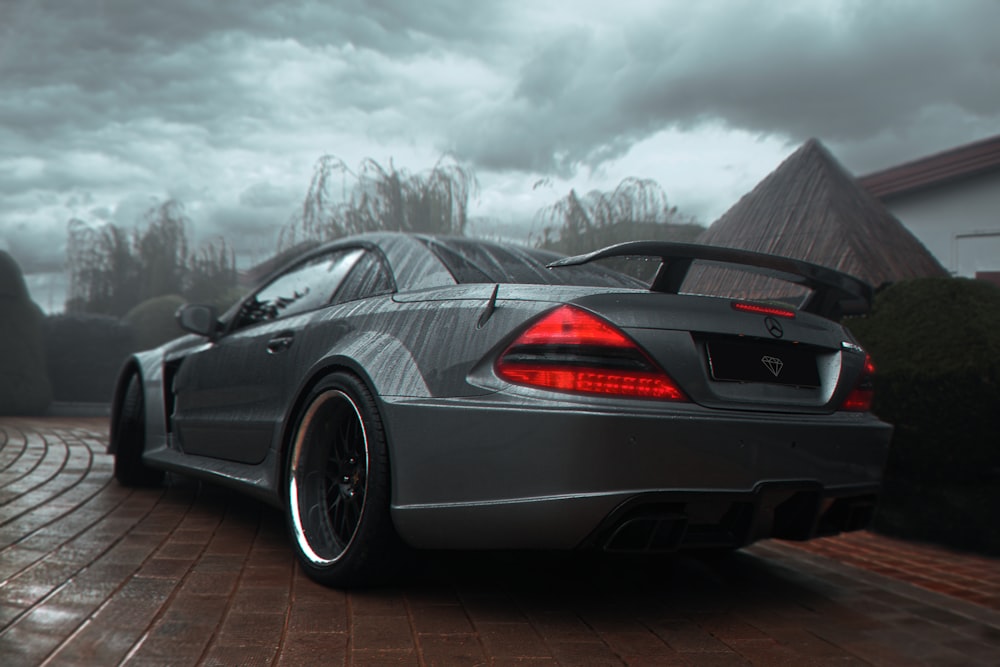 a grey sports car parked on a brick driveway