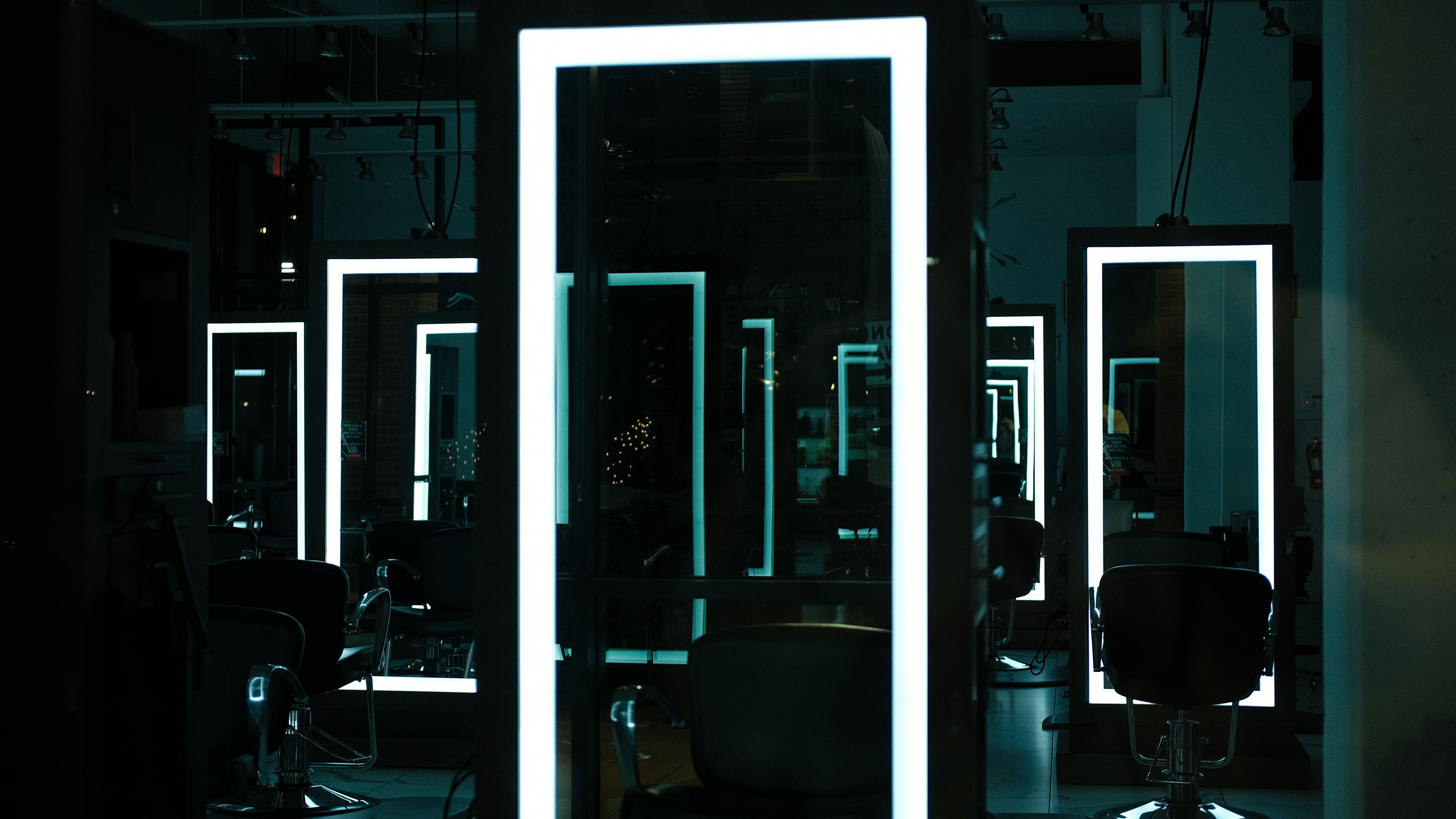 a hair salon with chairs and mirrors lit up