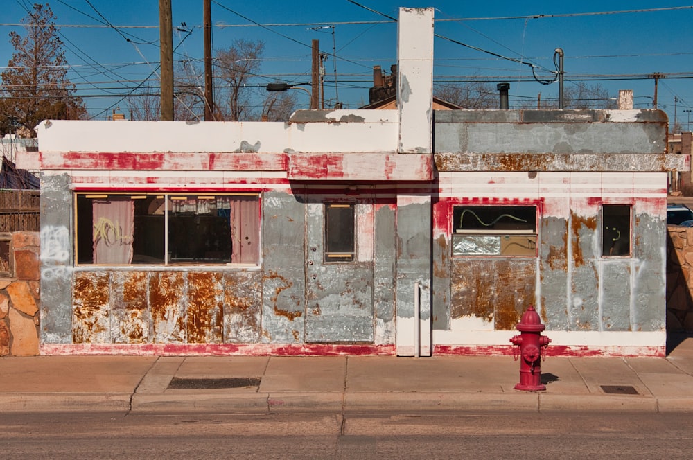 a red fire hydrant sitting in front of a run down building