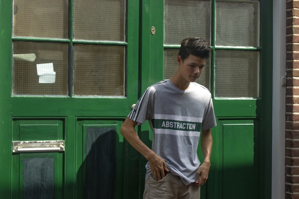 a young man standing in front of a green door