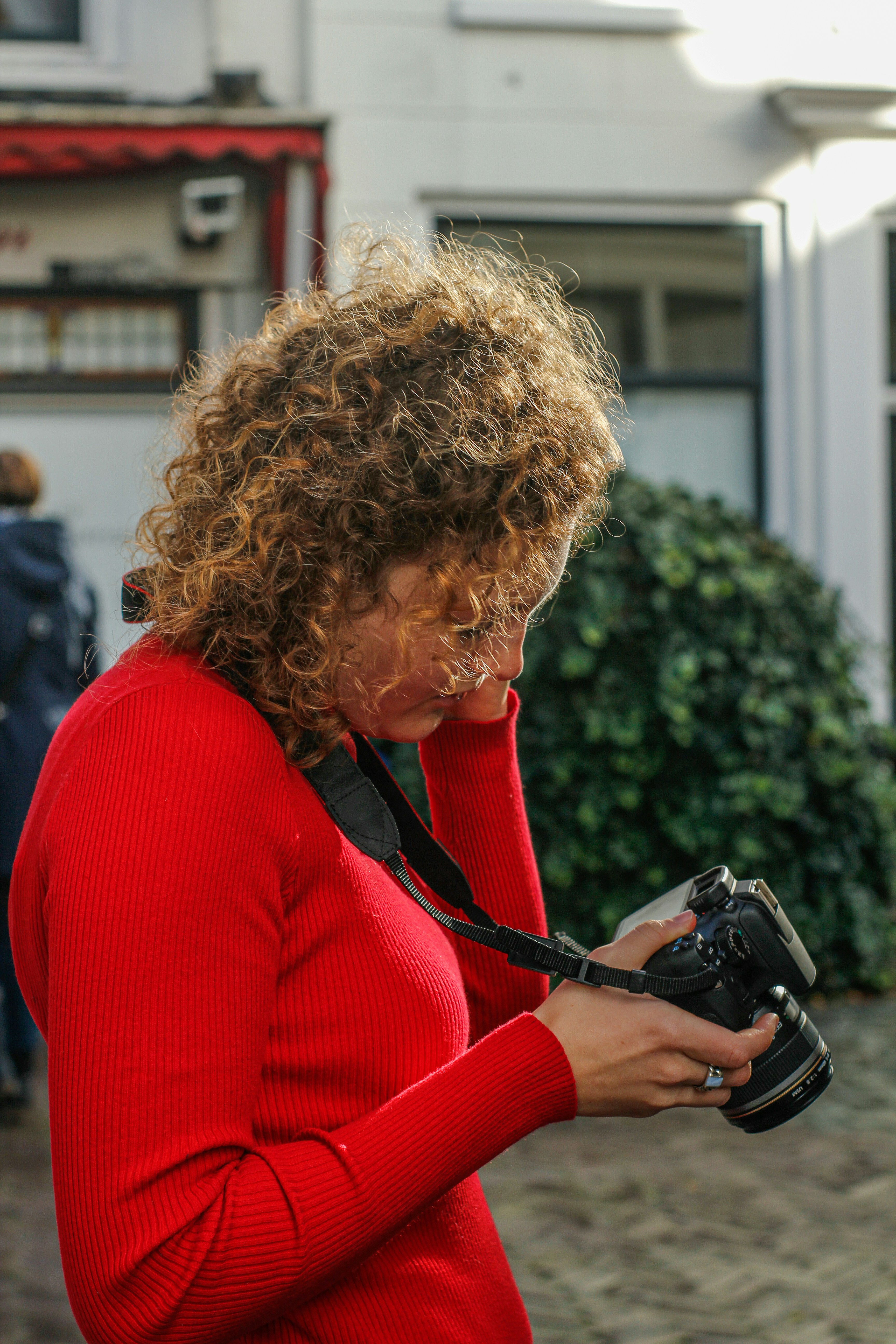 a woman in a red sweater holding a camera