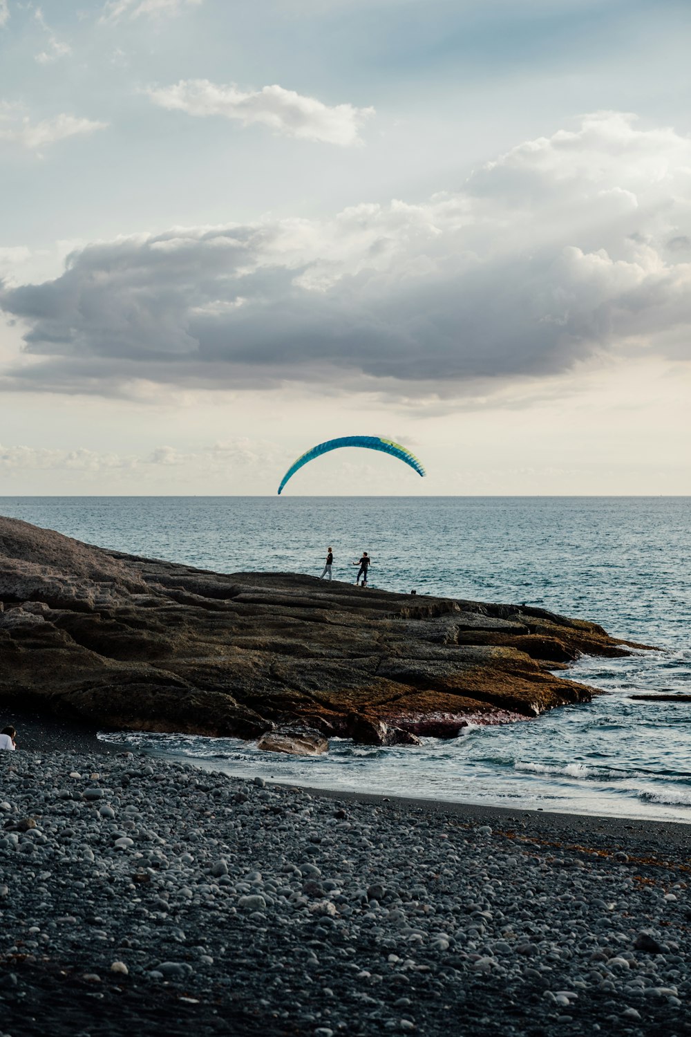 a couple of people standing on top of a rocky beach